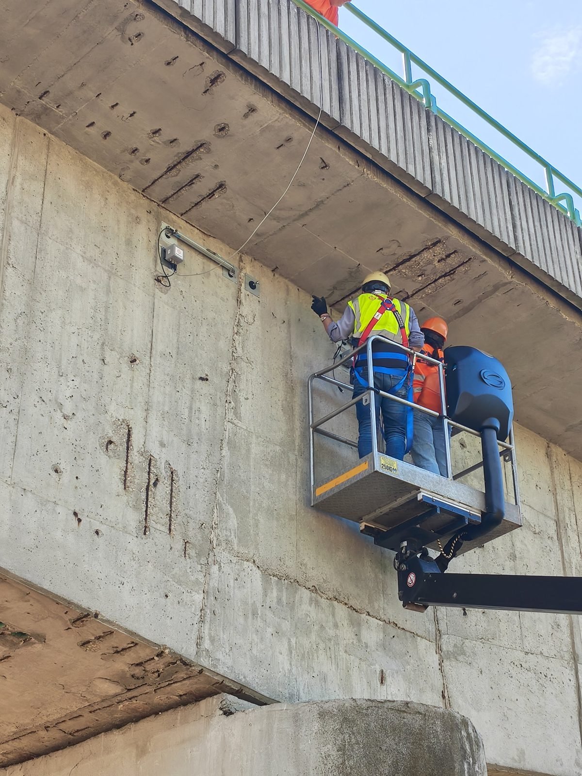Displacement sensor and data logger on the side of the bridge structure, installed from the basket of the bridge inspection vehicle